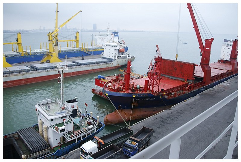 The ship on the left, unloading coal; on the right, specialised sub-sea cable reels