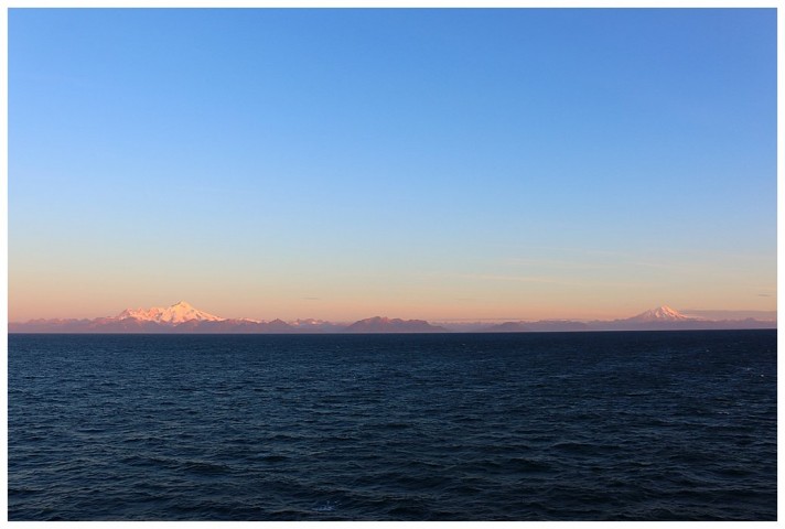 Cook inlet, the rising sun lighting volcanic, snow-clad mountains