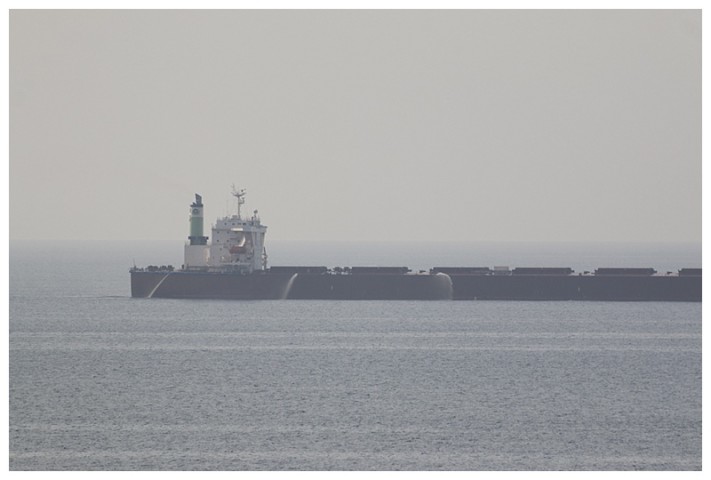Passing a slow bulk-carrier; she has her fire hoses running as a deterrent.  I have seen others, using their ballast tanks, overflowing the side with a waterfall down their entire length.  Nowadays many of them carry the best deterrent of all, armed security personnel.