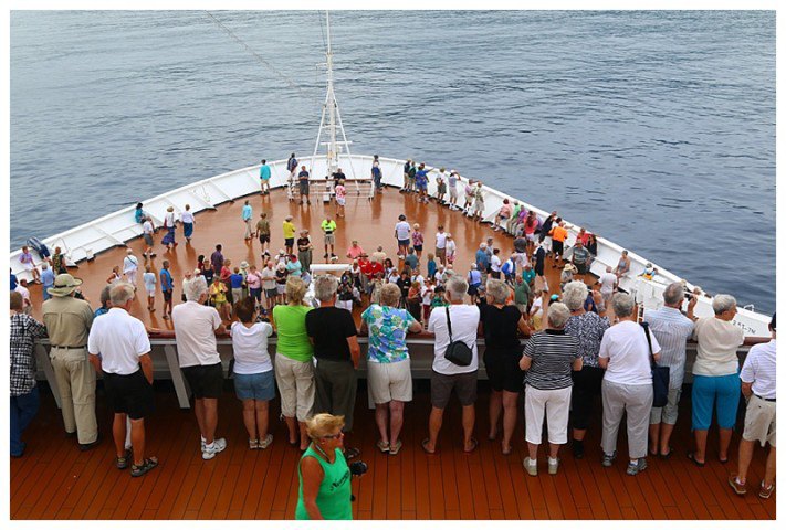 Guests on our foredeck and deck 6 watch Polynesian dancers, (who have sailed with us) as we approach the bay